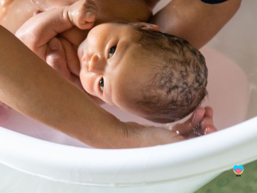 newborn baby having hair washed in bath