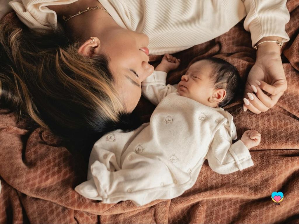 newborn baby laying next to mother looking at her